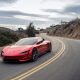 A red Tesla Roadster driving around a turn