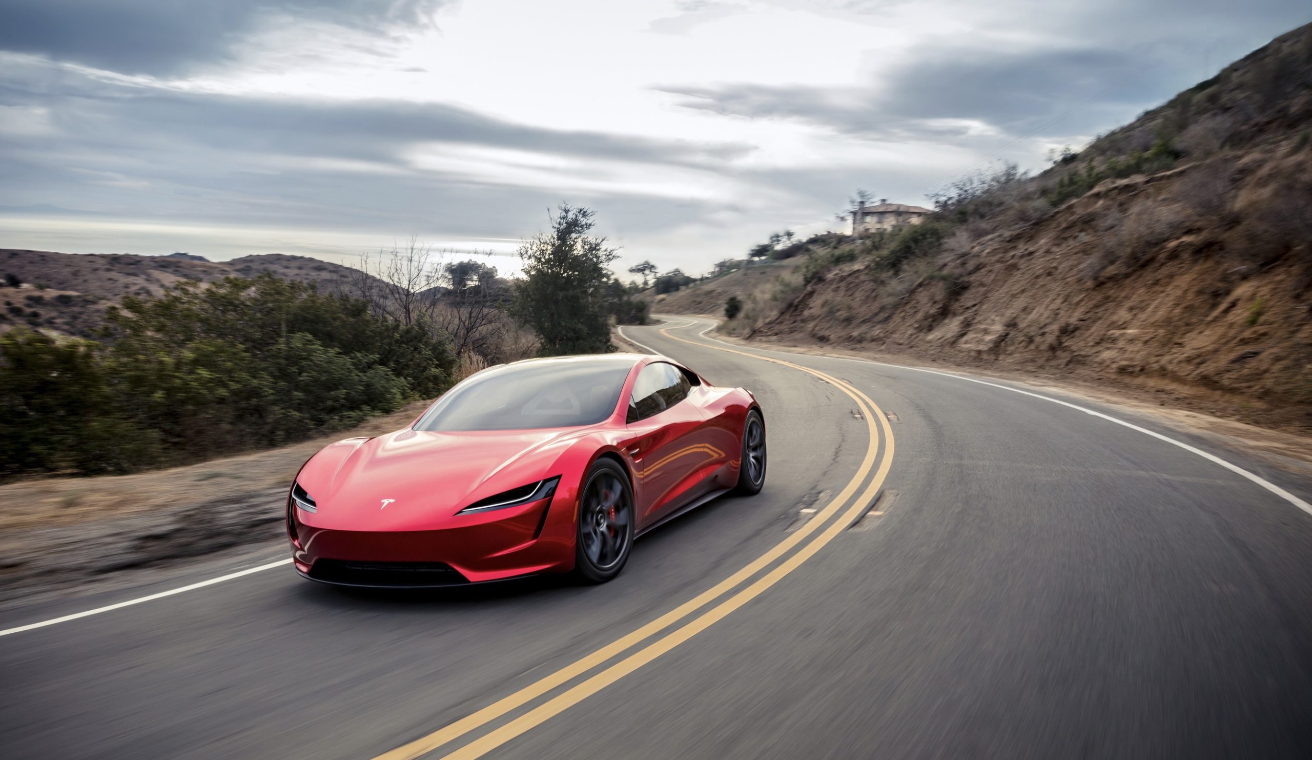 A red Tesla Roadster driving around a turn